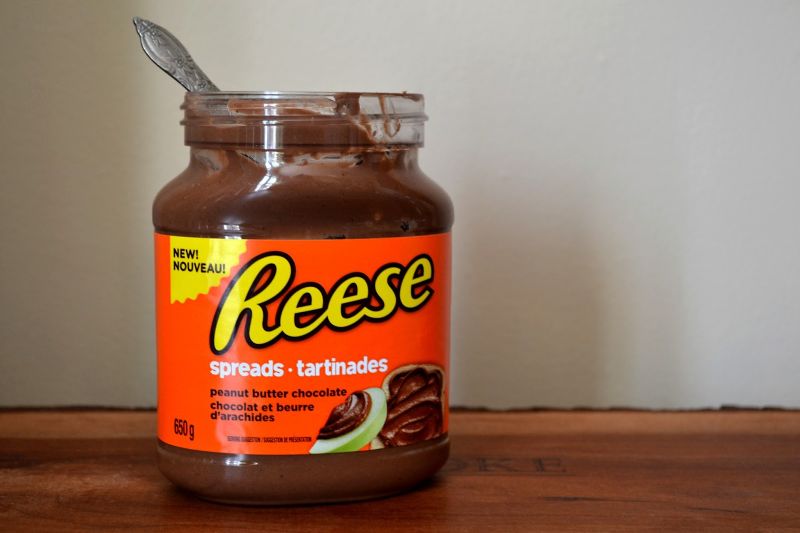 a jar of reese's peanut butter chocolate spread with a spoon in it- reese's spread