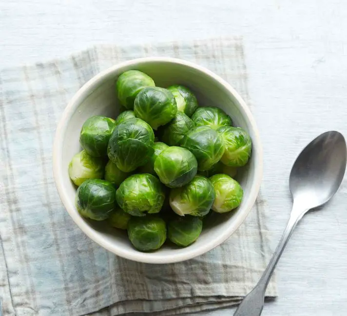 brussels sprouts in a bowl with a spoon placed beside it 
