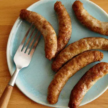 cooked sausages in a plate with a fork