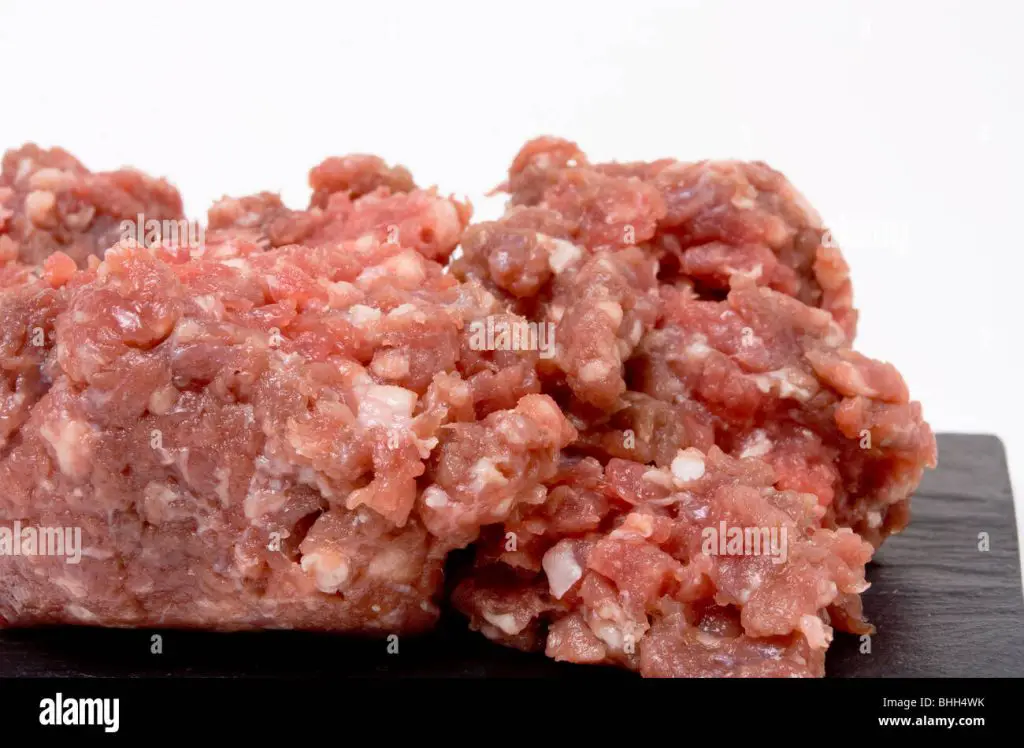 gristly ground or minced beef from low viewpoint up close against white background