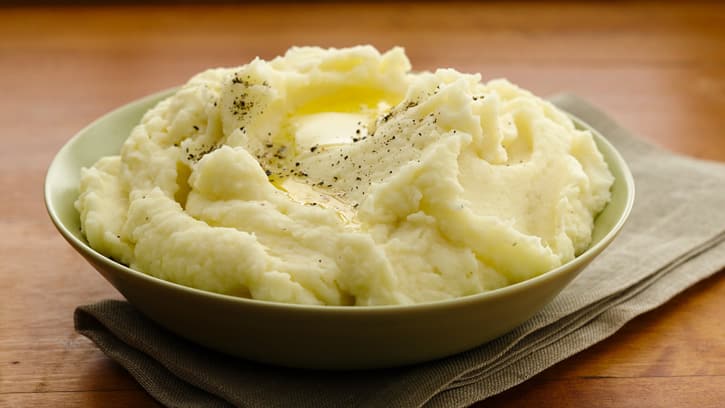 mashed potatoes in a bowl placed on a wooden surface