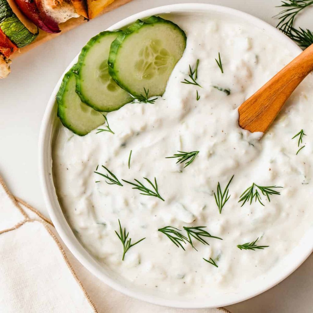 tzatziki sauce in a bowl with some slices of cucumber in it 