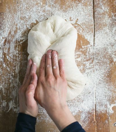a woman shaping sourdough with her fingers