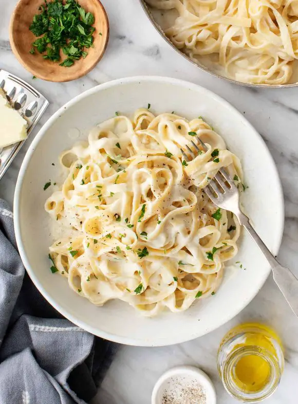 fettuccine alfredo served in a plate with fork 