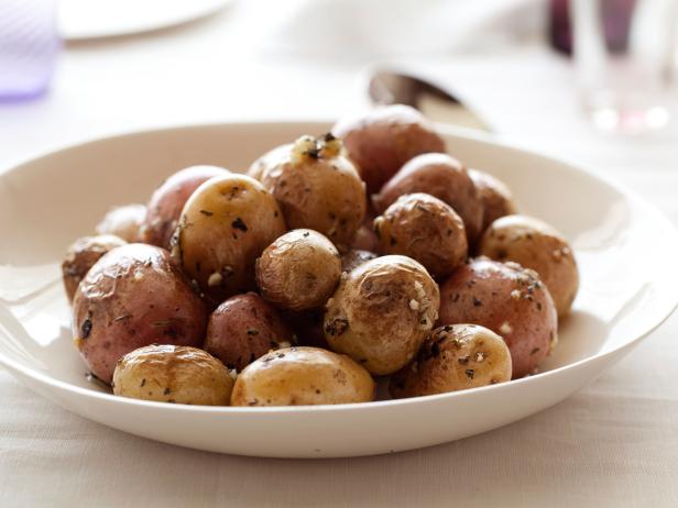 roasted baby potatoes in a plate with mixed herbs sprinkled on them 